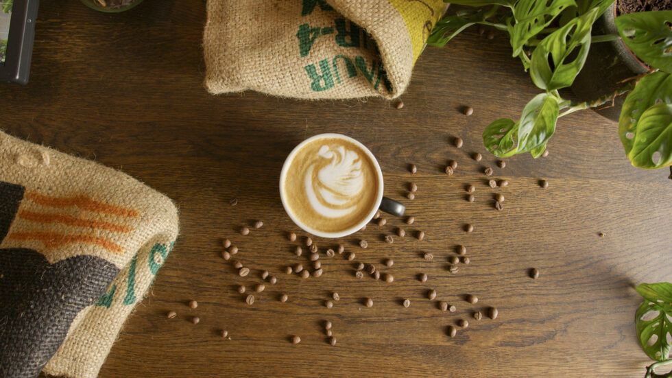 Kaffeetasse mit Latte Art und Kaffeebohnen verziert